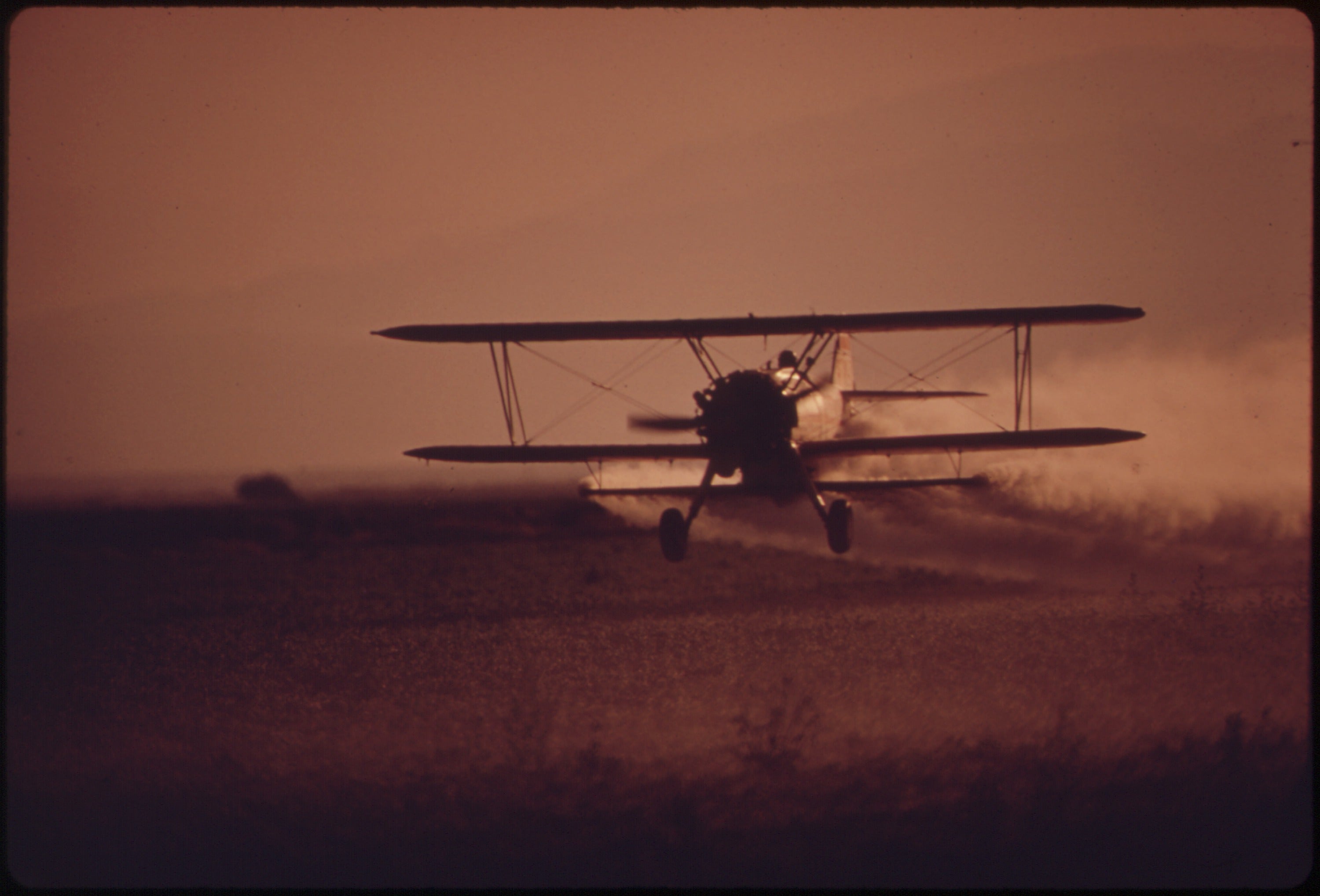 Crop-duster plane spraying a field