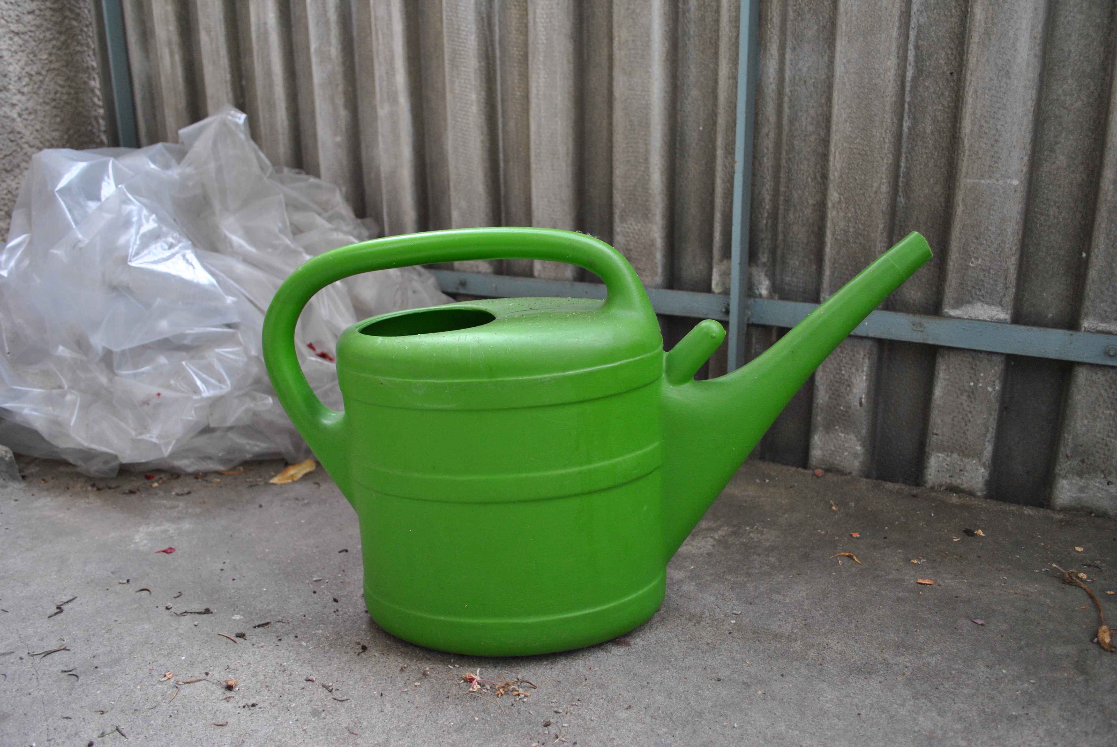 A watering can being used to water a garden bed